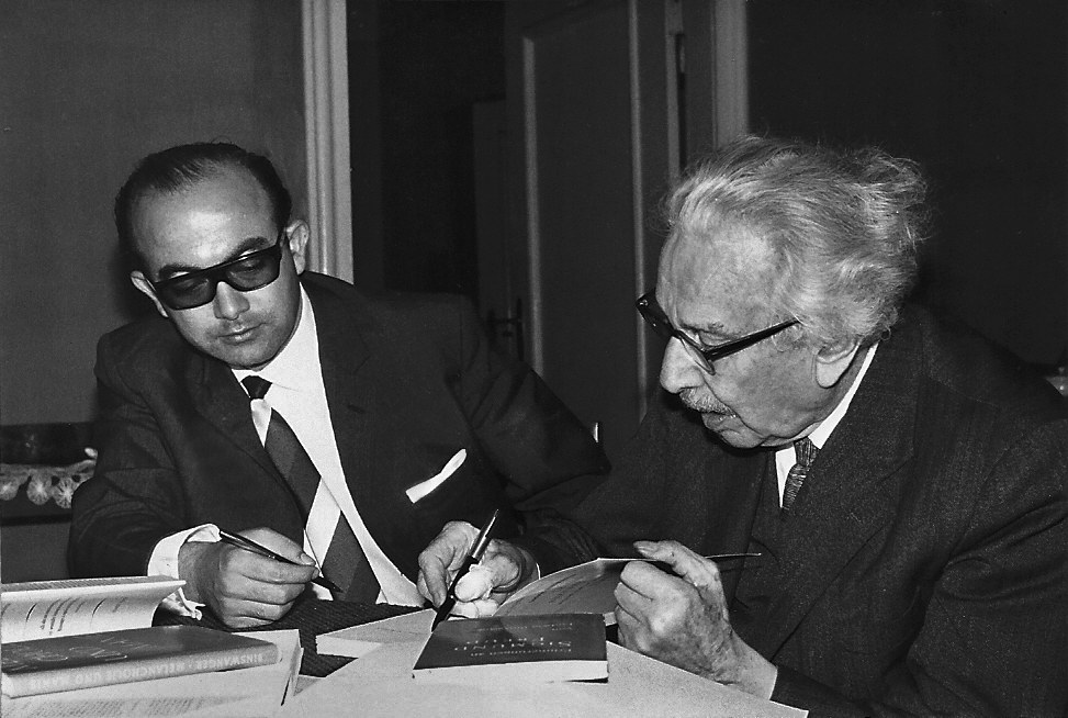 Fotografía en blanco y negro de 1964: Alfonso Caycedo y Ludwig Binswanger trabajan juntos sobre unos libros abiertos, en Kreuzlingen