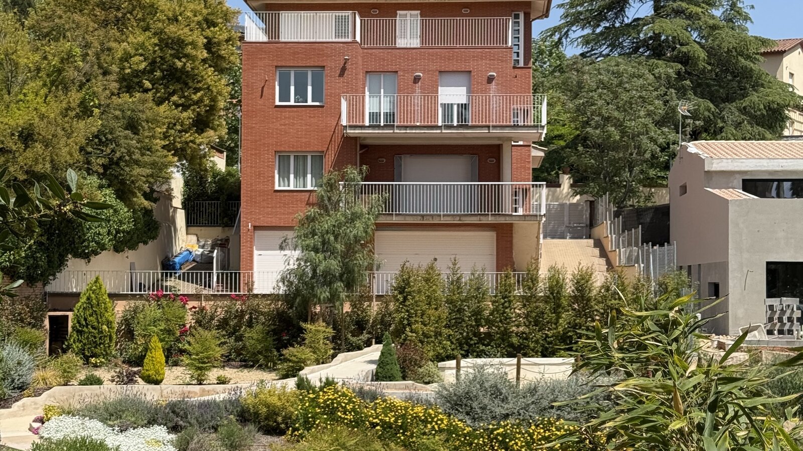 Instituto Caycedo en Bellaterra, Barcelona — fachada de ladrillo con jardín mediterráneo