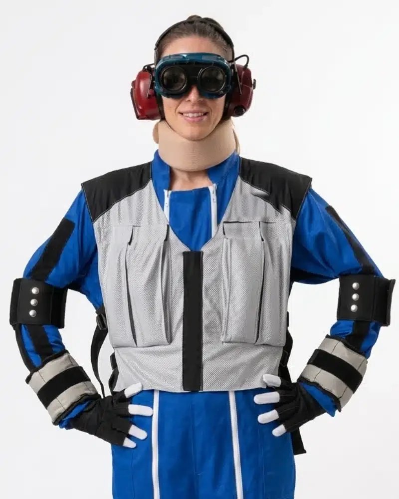 Persona con el traje de simulación del envejecimiento: gafas que alteran la vista, protectores auditivos, collarín, chaleco lastrado y limitadores en codos y muñecas